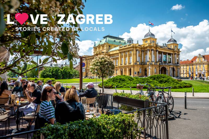 Zagreb city on a sunny day. A view of people sitting on a terrace, talking and laughing. They terrace is in front of Croatian National Theatre in Zagreb.